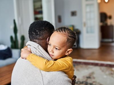 A young child hugs a man